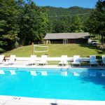 Outdoor pool with chairs and volleyball court in background - English Mountain Recovery