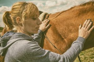Holistic Addiction Treatment in Recovery, woman petting tan horse - holistic