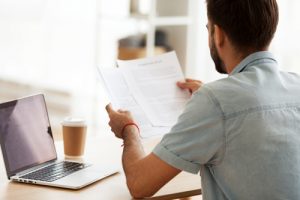 man reading papers in front of laptop - family medical leave act
