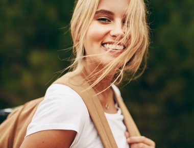 pretty smiling young blonde woman wearing backpack