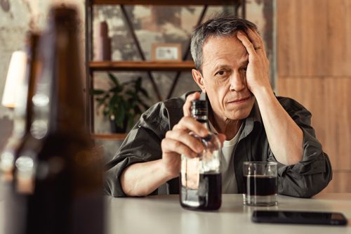 senior man drinking alcohol at home - binge drinking