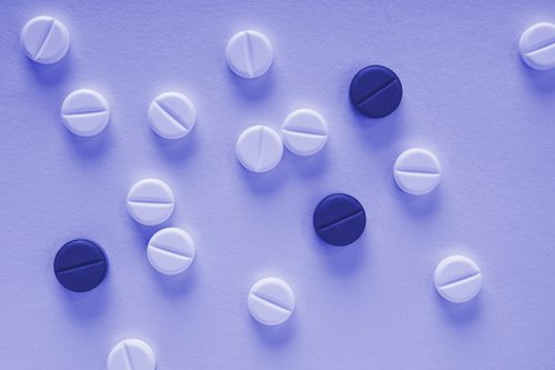 scored white and purple tablets on purple background - morphine addiction